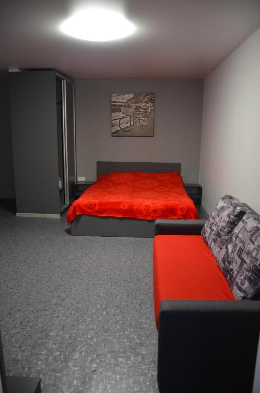ein Schlafzimmer mit einem roten Bett und einem Sofa in der Unterkunft Апартаменты на Александра Поля (Кирова) 90 in Dnipro
