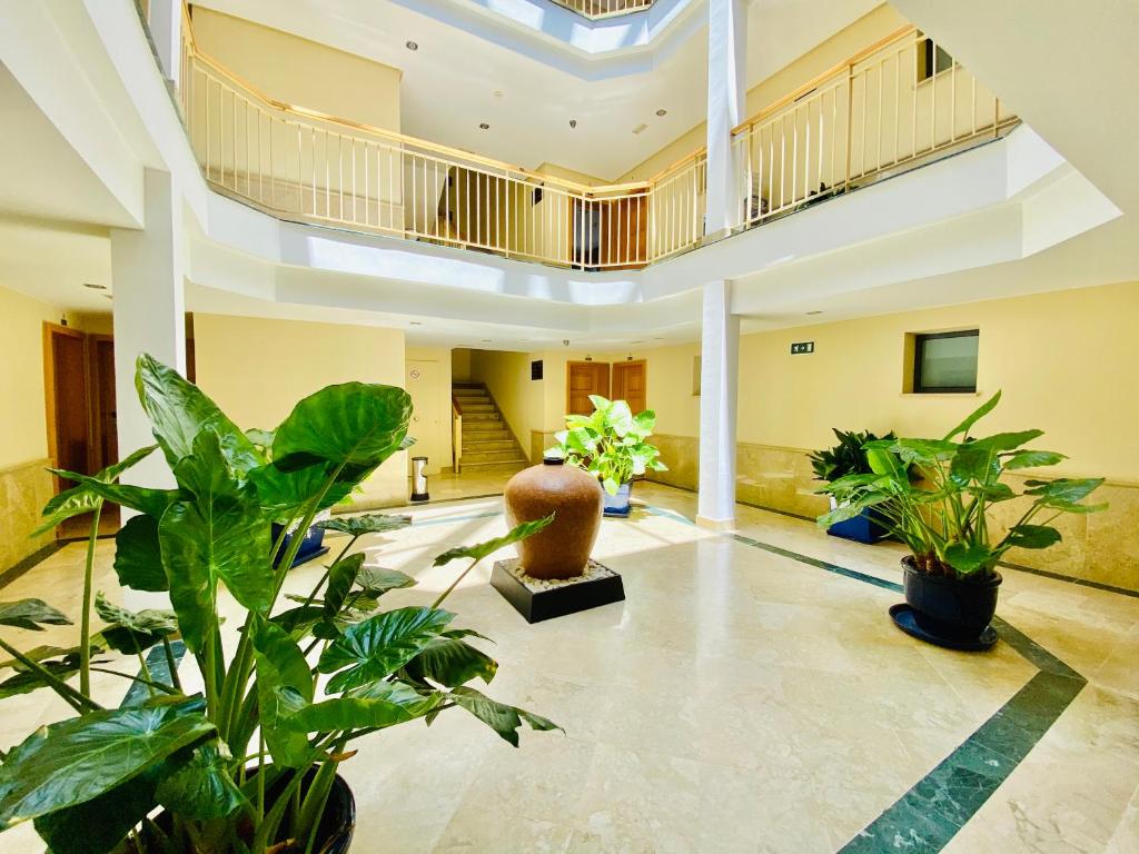 a lobby with potted plants and a staircase at Hotel Apartamentos Marina Luz in Chipiona