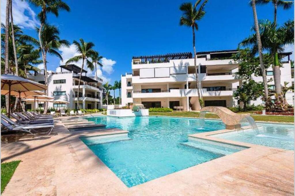 a swimming pool in front of a building with palm trees at Oasis Apartment C4 inside ALIGIO Residence Hotel in Las Terrenas