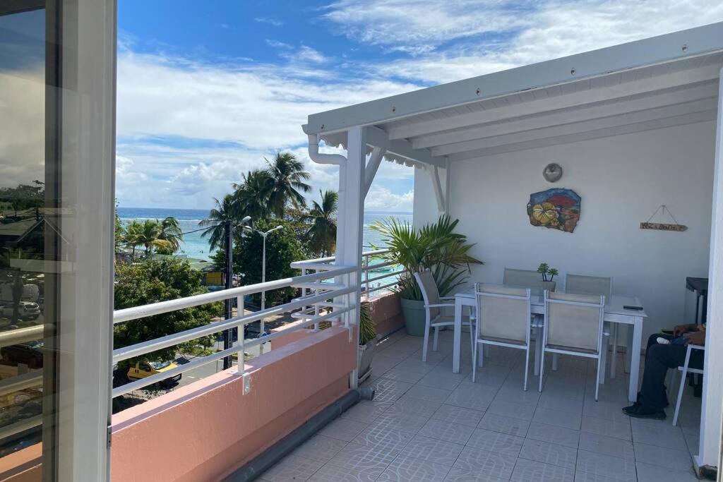 einen Balkon mit einem Tisch und Meerblick in der Unterkunft Appartement bord de mer in Sainte-Anne