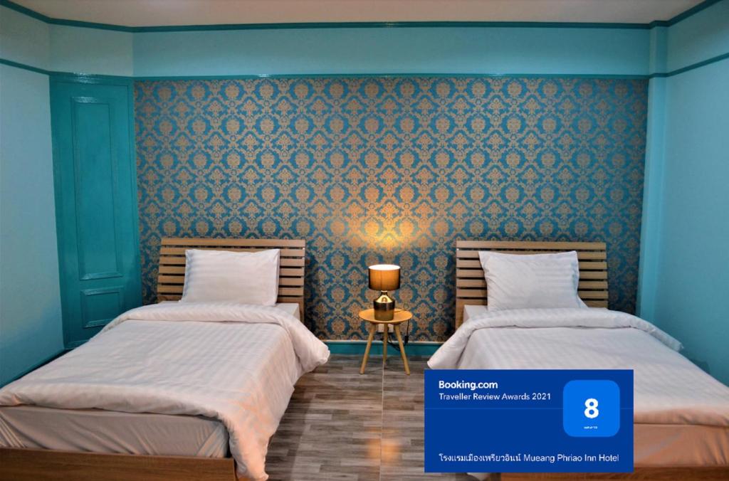 two beds in a room with blue walls at โรงแรมเมืองเพรียวอินน์ Mueang Phriao Inn Hotel in Sara Buri