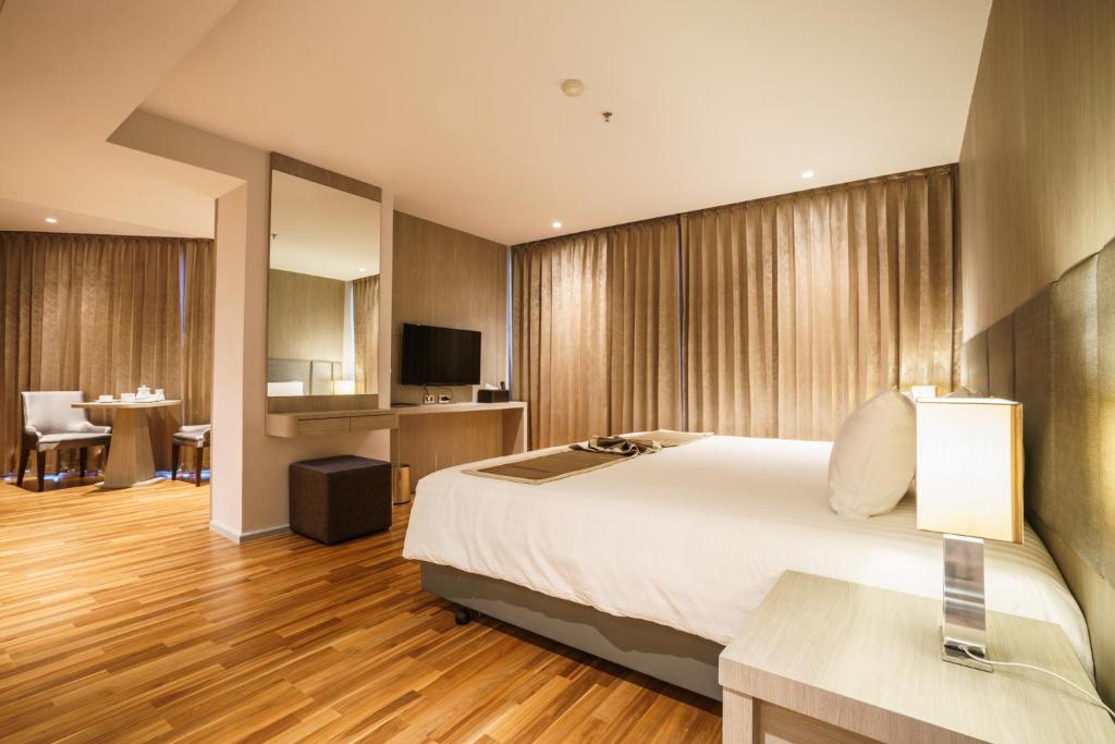 ein Hotelzimmer mit einem großen Bett und einem Tisch in der Unterkunft New Season Square Hotel - SHA Plus in Hat Yai