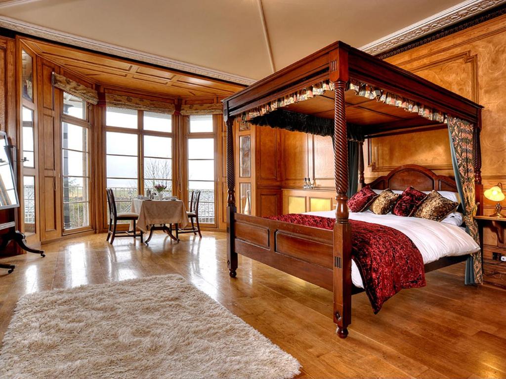 Bay Villa في غرانج أوفر ساندز: غرفة نوم مع سرير مظلة وغرفة طعام