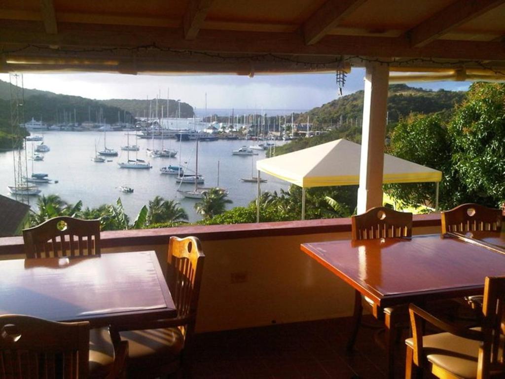 2 mesas y sillas en un porche con vistas al puerto en The Ocean Inn Antigua, en English Harbour Town