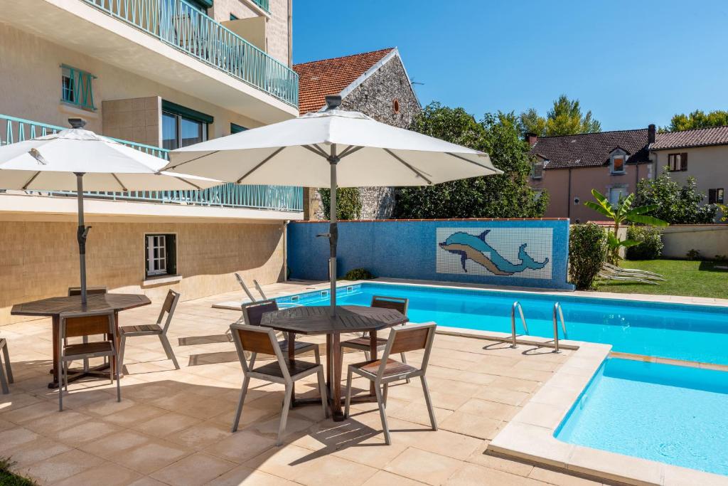 two tables and chairs with umbrellas next to a pool at Le Quercy in Souillac