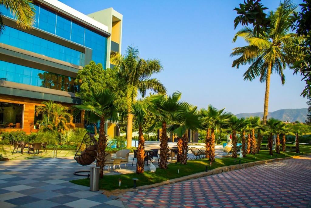 een resort met palmbomen voor een gebouw bij The Bhagwati Resort in Abu Road