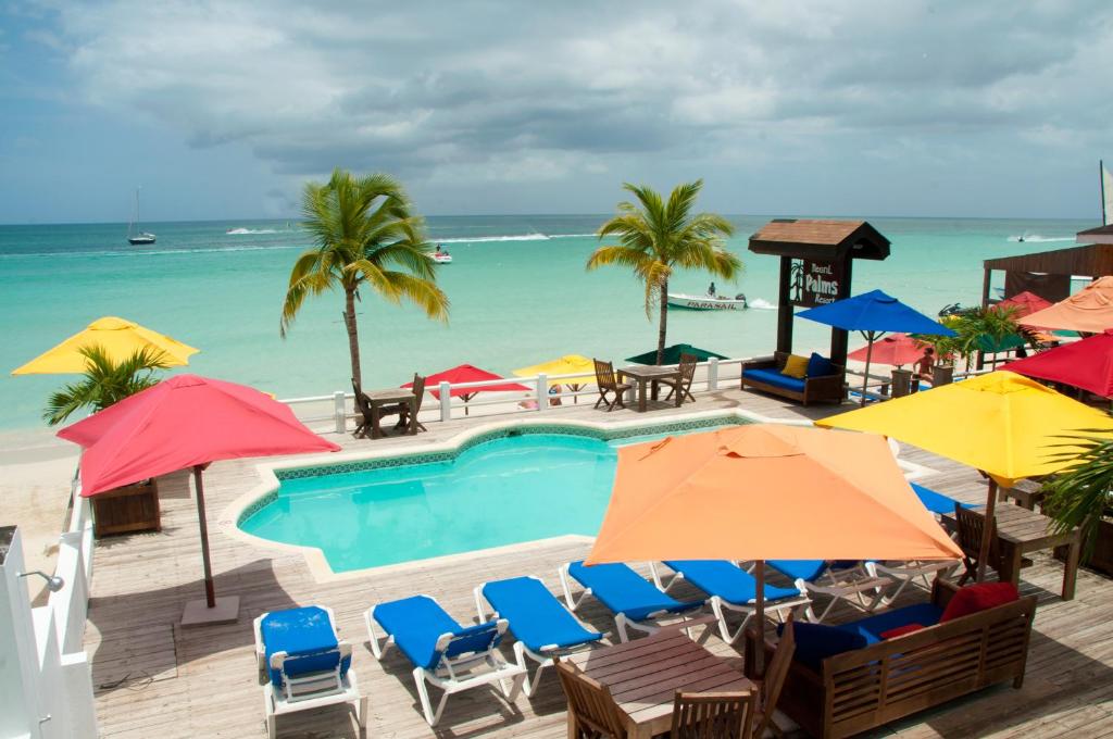 a swimming pool with umbrellas and chairs and the ocean at Negril Palms in Negril