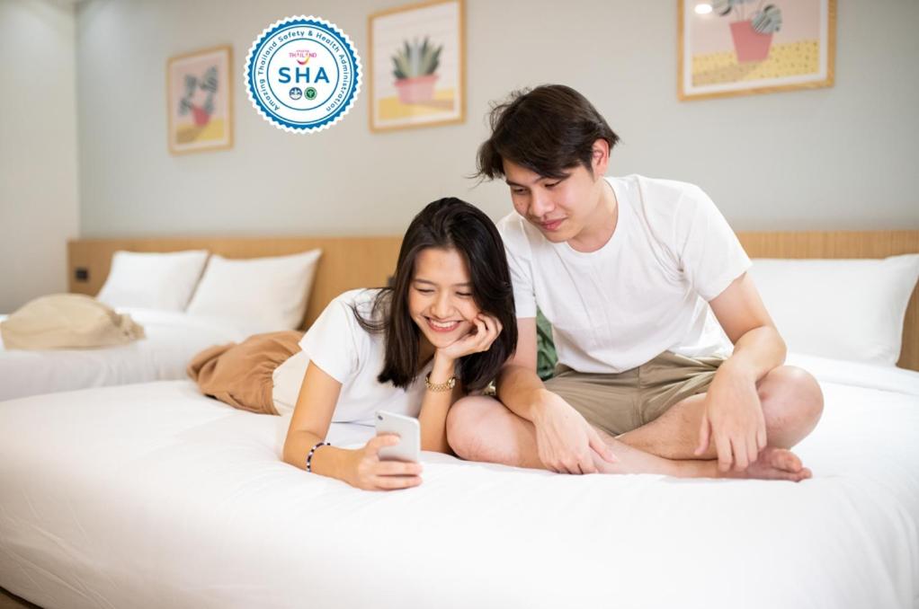 un hombre y una mujer sentados en una cama en Cubic Bangna, en Bangkok