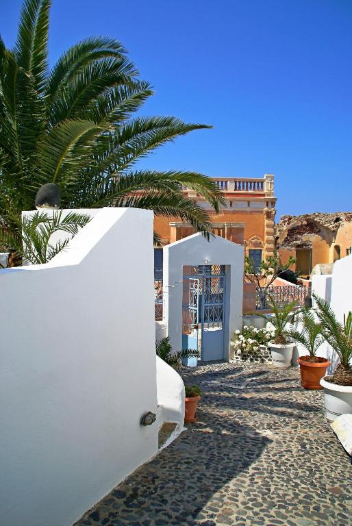 een wit gebouw met een palmboom ervoor bij Aethrio Sunset Village - Oia in Oia