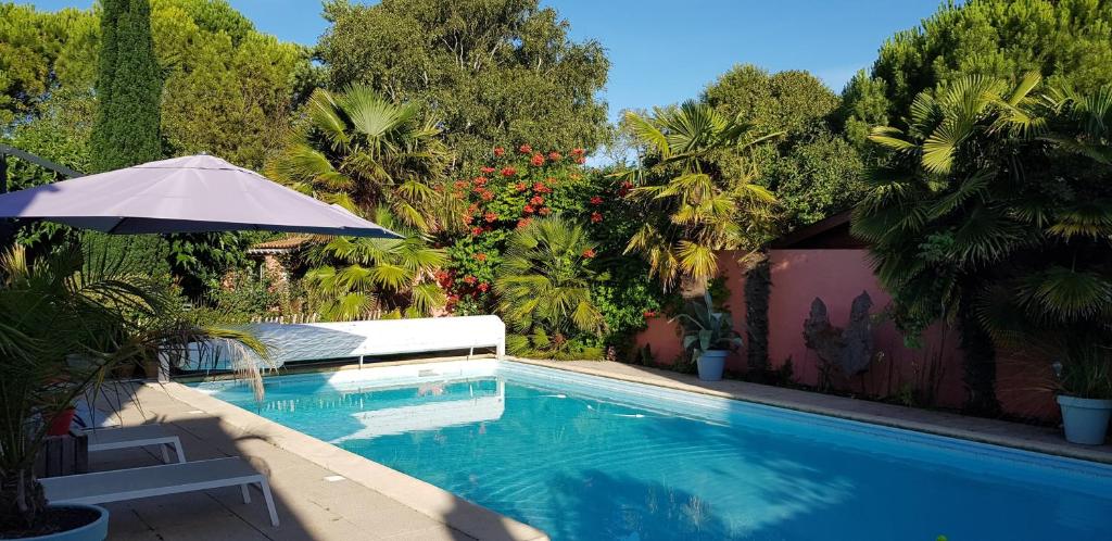 ein Pool mit einem Sonnenschirm und einem Stuhl daneben in der Unterkunft Gîtes, Chambres d'Hôtes La Maison d'Amis in Puilboreau