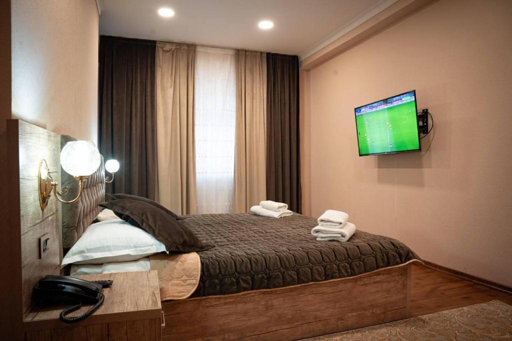 um quarto com uma cama e uma televisão na parede em Dream Inn H&A em Tashkent