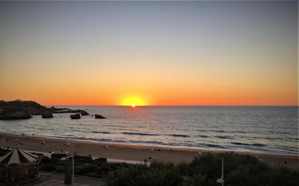 a sunset on the beach with the sun setting at Victoria Surf Biarritz 102 in Biarritz