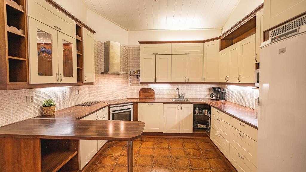 a kitchen with white cabinets and a wooden counter top at Hotel Aakenus Holiday Home Koivu in Rovaniemi