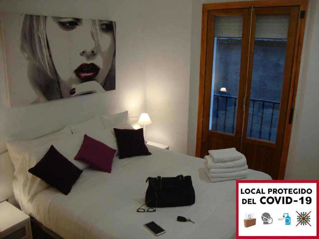 una camera con un letto bianco e una foto appesa al muro di Calle Ansoleaga a 100 mts del Ayuntamiento a Pamplona