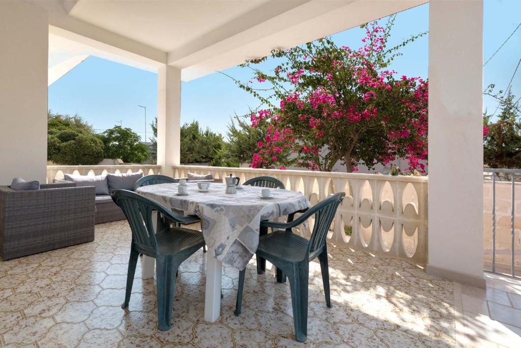 a table and chairs on a patio with pink flowers at Casa Bouganville by BarbarHouse in San Pietro in Bevagna