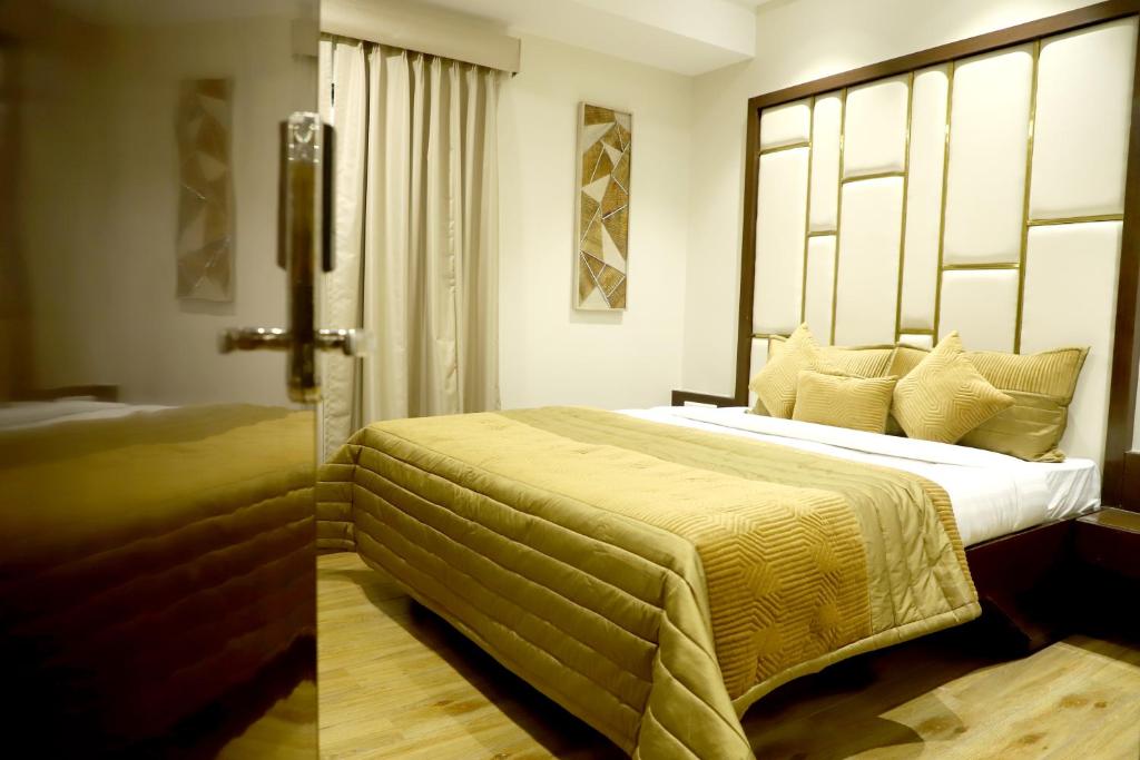 インドールにあるHotel Grand Girdharのベッドルーム1室(大型ベッド1台、黄色のベッドカバー付)