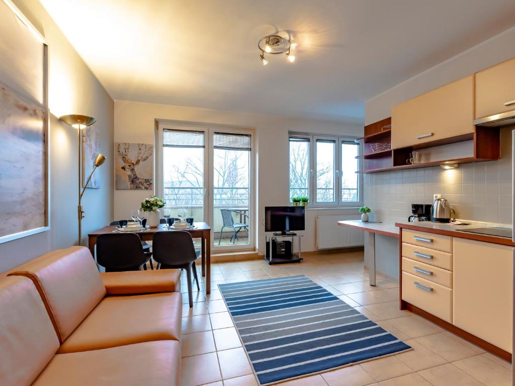 a kitchen and living room with a couch and a table at VacationClub - Zielone Tarasy Apartament 51 in Kołobrzeg