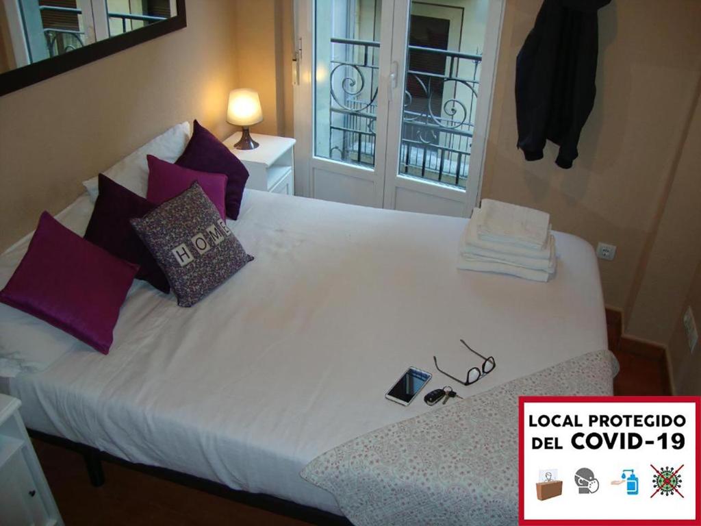 1 cama blanca grande con almohadas y ventana en Balcón curva de Estafeta - Centro en Pamplona