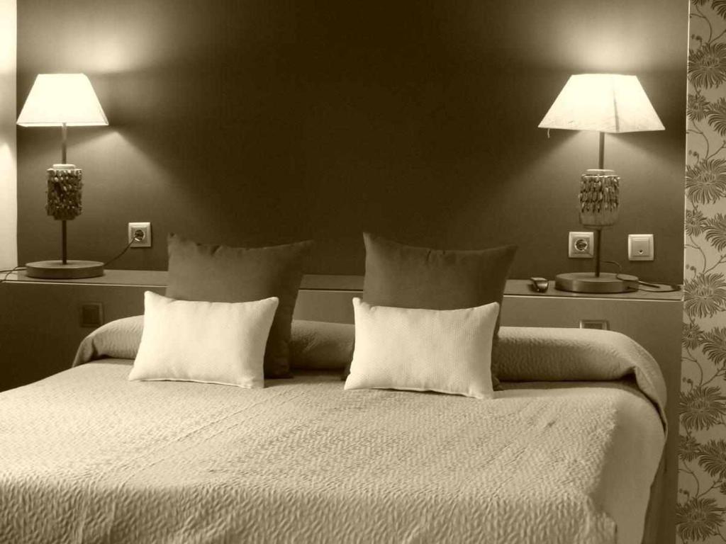 una camera con un grande letto con due lampade di La casa de Don a Pedraza-Segovia