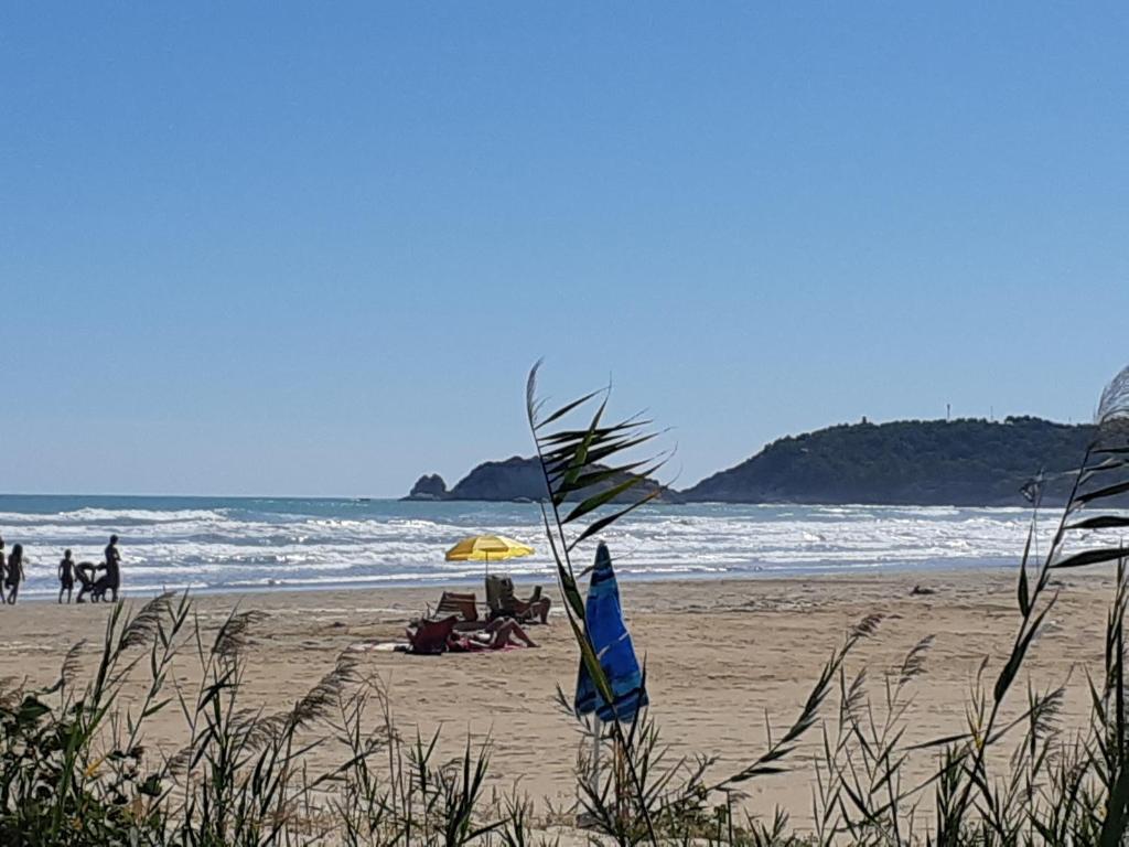 a beach with people sitting on the sand and an umbrella at La Dimora in riva al mare in Vieste