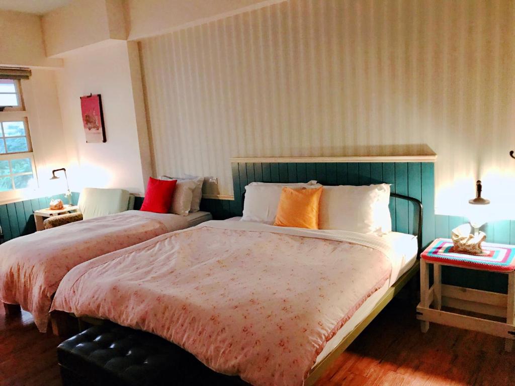 a bedroom with two beds and a table with a lamp at MiCarro B&amp;B in Dongshan