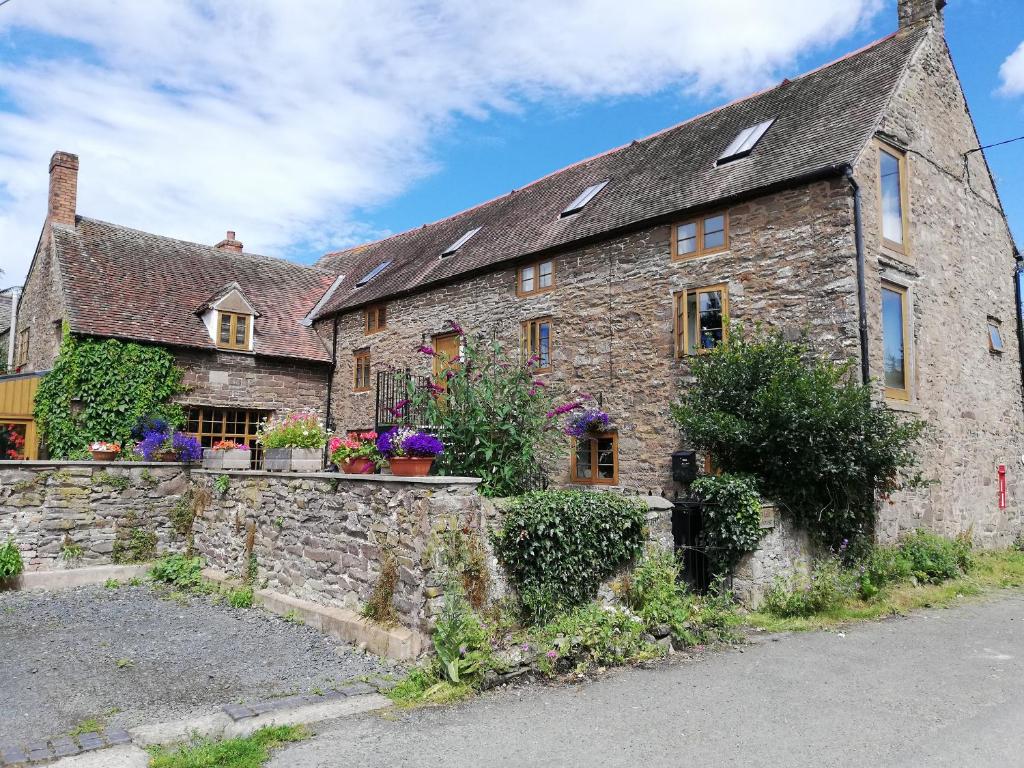 an old stone house with a stone wall at The Gallery in Craven Arms