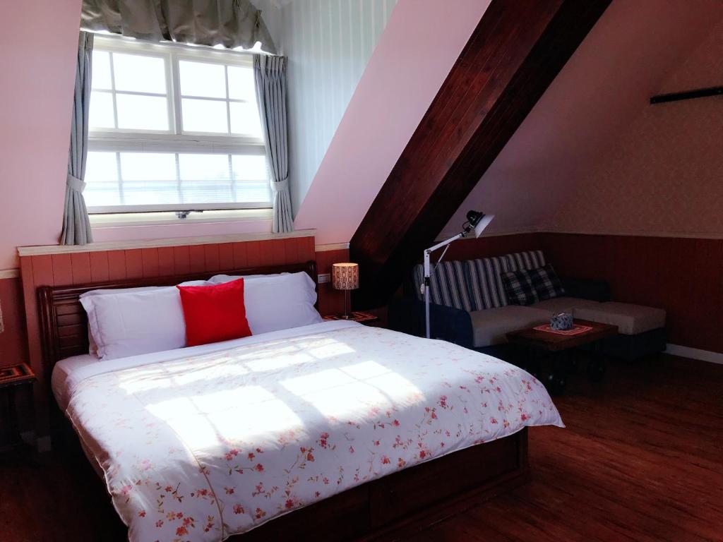 a bedroom with a bed with red pillows and a window at MiCarro B&amp;B in Dongshan