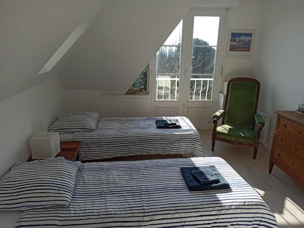 ゲランドにあるMaison des rempartsのベッド2台、椅子、窓が備わる客室です。
