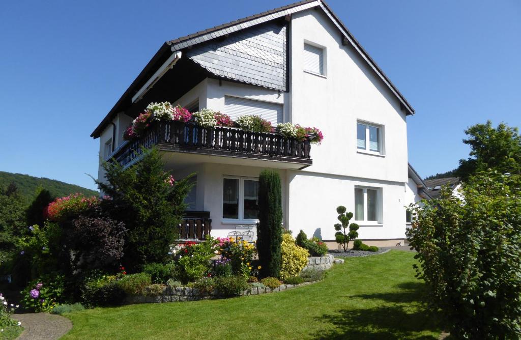 ein weißes Haus mit einem Balkon mit Blumen in der Unterkunft Ferienwohnung Waltraud in Brilon