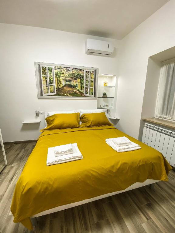 a bedroom with a yellow bed with two towels on it at Exclusive Mood Apartment in Rome