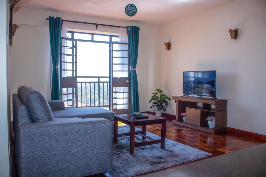 salon z kanapą, telewizorem i stołem w obiekcie Kasty T Apartments- W Place w mieście Nairobi