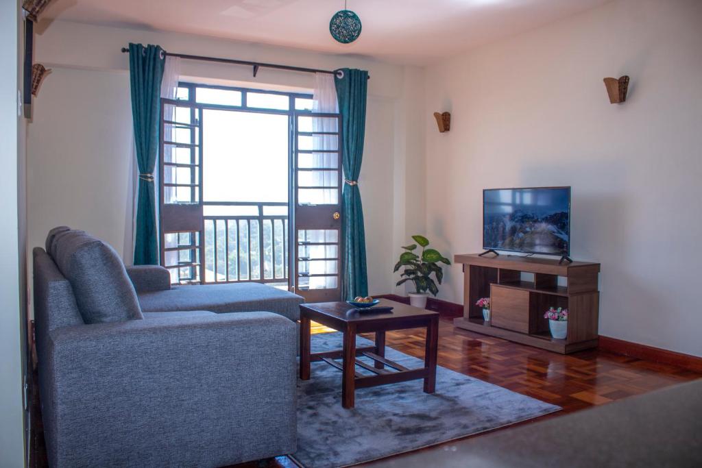 een woonkamer met een bank, een tv en een tafel bij Kasty T Apartments- W Place in Nairobi