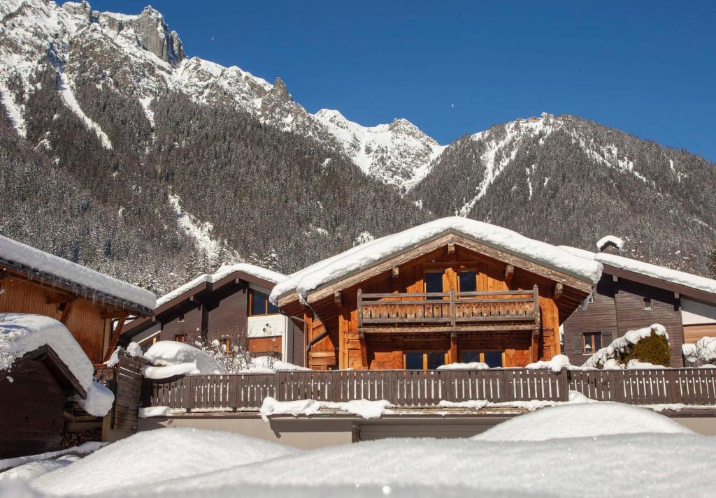 a log cabin covered in snow with mountains in the background at Chalet La Chaumière in Chamonix