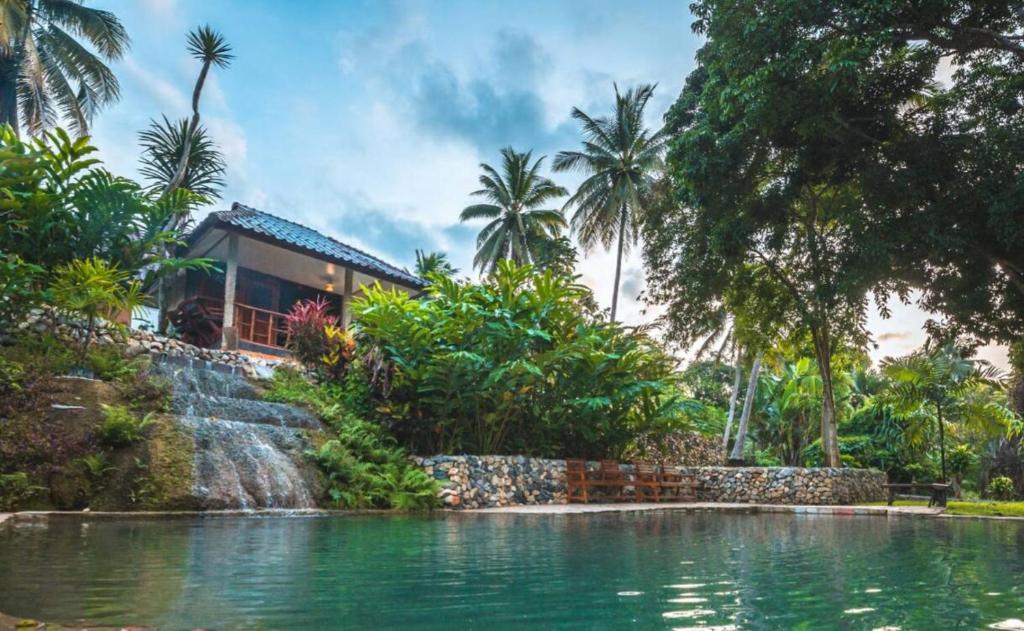 uma casa com uma cascata junto a uma piscina em NonKan HomeStay นอนกาญจน์ โฮมสเตย์ em Kanchanaburi