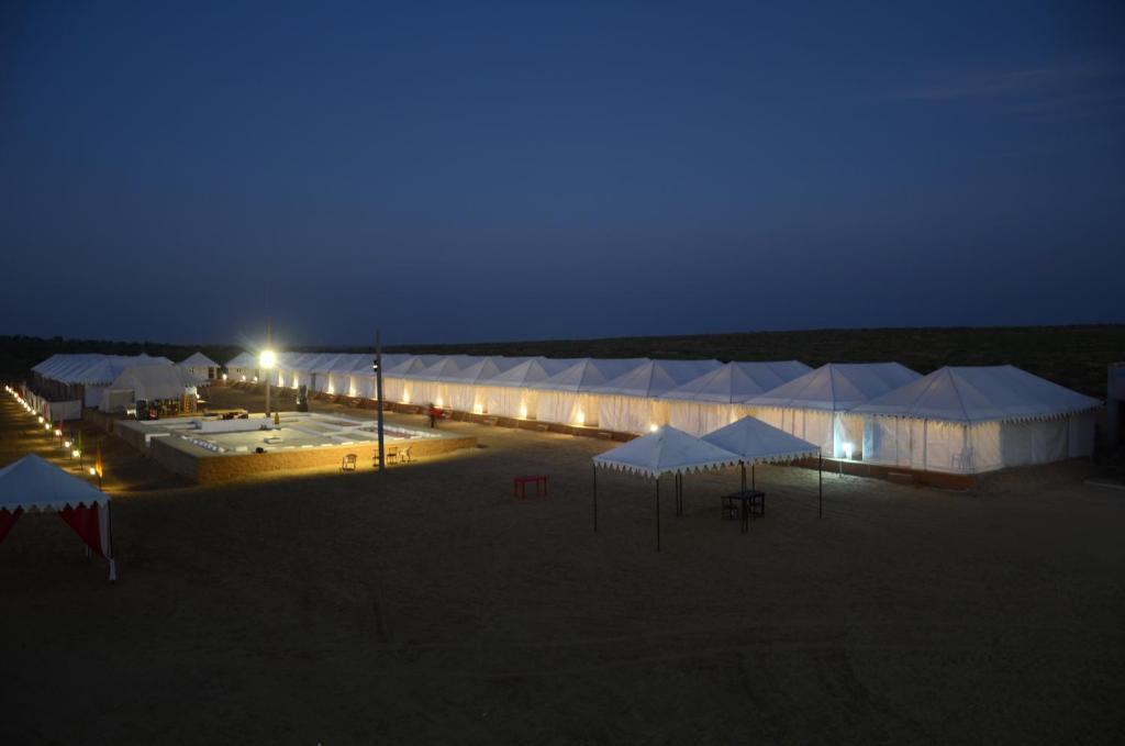 a group of tents in a field at night at Sky Desert Safari in Sām