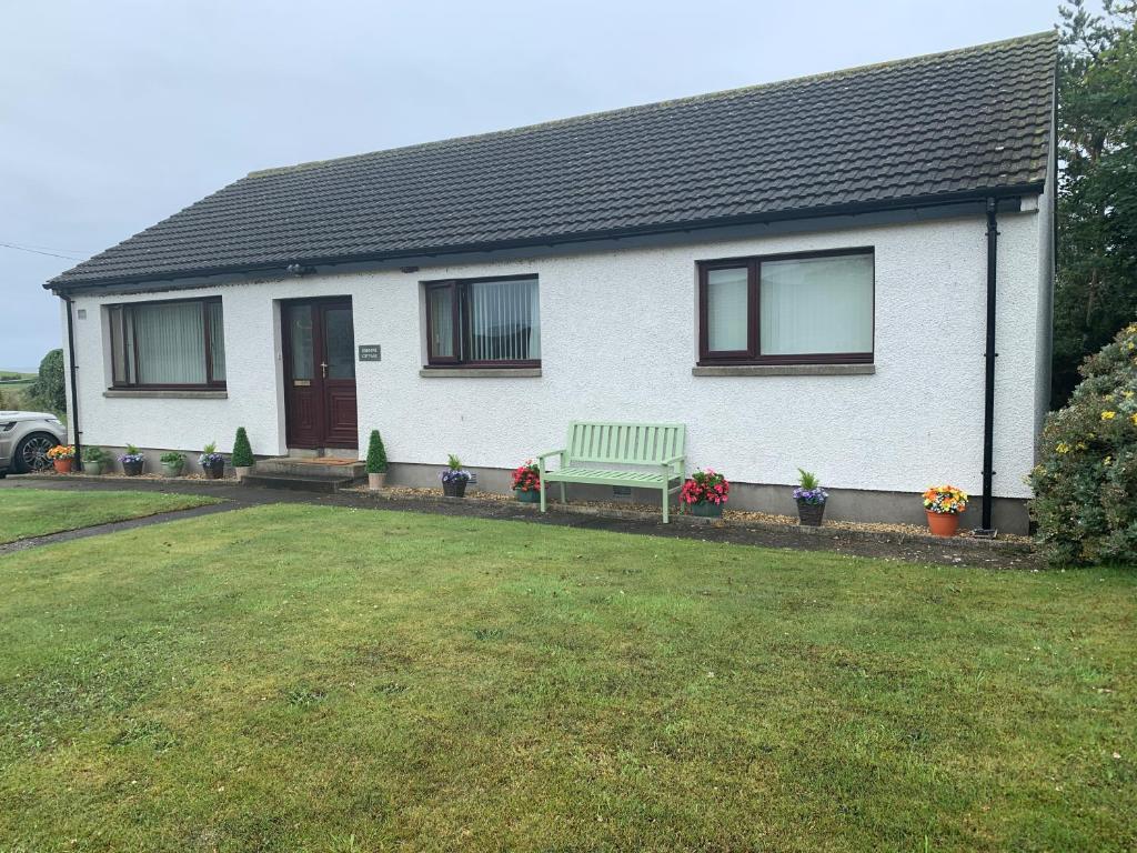 een wit huis met een groene bank in de tuin bij Osborne Cottage in Southend