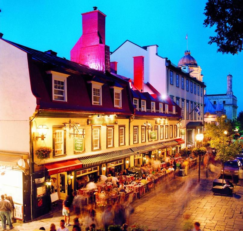 un grupo de personas caminando por la calle por la noche en Auberge du Trésor, en Quebec