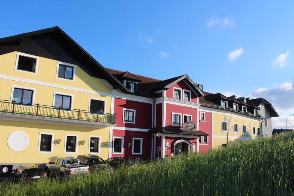 a row of colorful buildings on a grassy hill at Mohnhotel - Bergwirt Schrammel in Zwettl Stadt