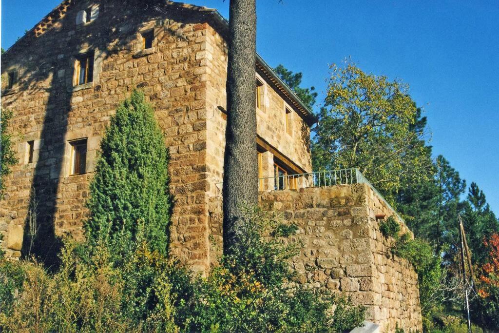 un bâtiment en briques avec un arbre devant lui dans l'établissement Belle et grande maison ardèchoise, à Payzac