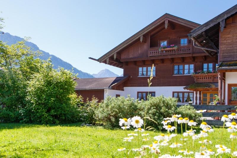 a house with a field of flowers in front of it at Ferienwohnung Heidi Steinbacher inkl. Chiemgaukarte in Ruhpolding