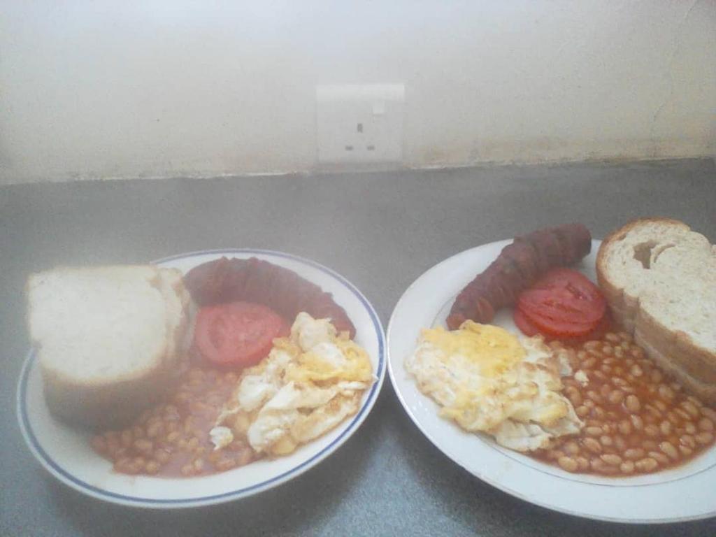 deux assiettes de petit-déjeuner avec des œufs, des haricots et du pain dans l'établissement Naumba Camp and Campsite, à Ngoma