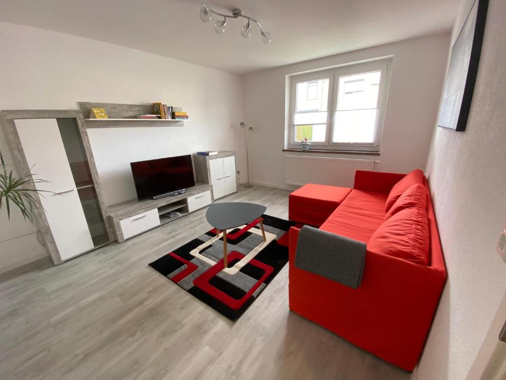 uma sala de estar com um sofá vermelho e uma televisão em Schöne Ferienwohnung in Landsberg em Landsberg