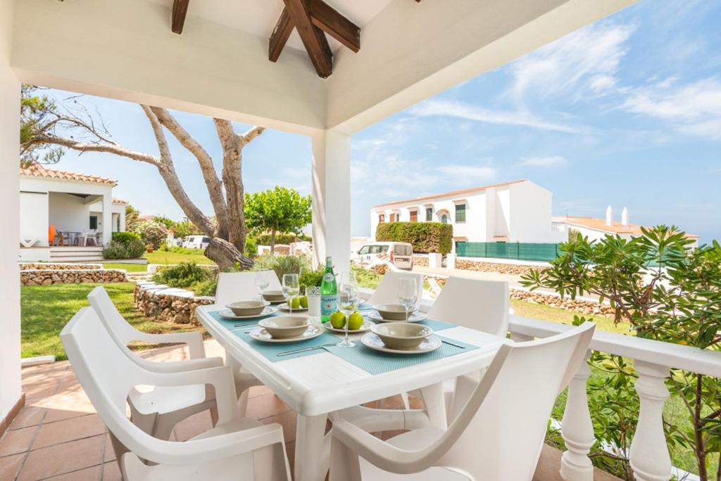 a white dining table and white chairs on a patio at Arenal Jardín 56-2 - Arenal den Castell in Arenal d'en Castell