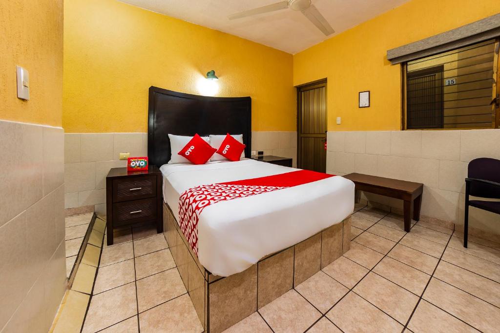 um quarto com uma cama grande e almofadas vermelhas em Hotel San Marcos em Los Mochis