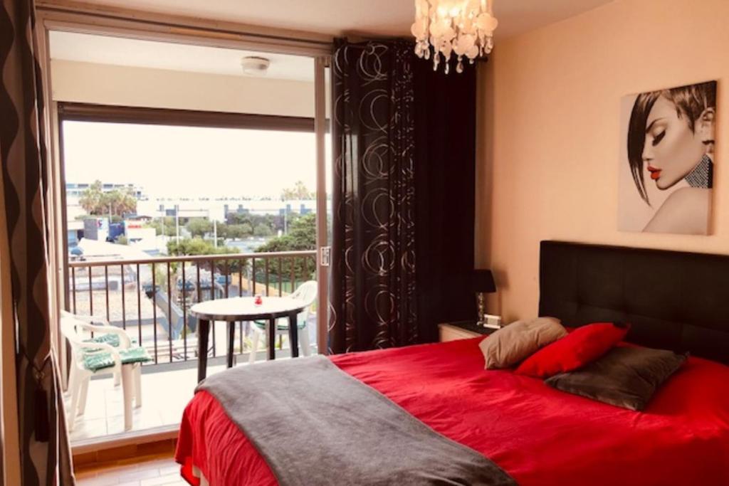 een slaapkamer met een rood bed en een balkon bij Cap d' Agde Naturiste Héliopolis F31 in Cap d'Agde