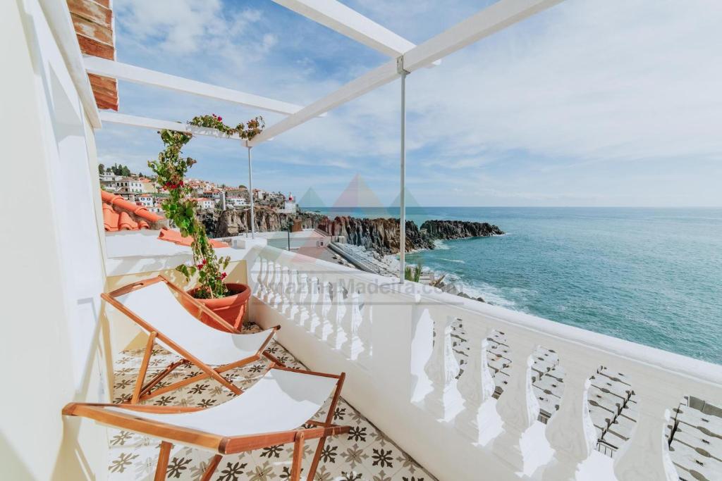 a balcony with chairs and a view of the ocean at Casa da Praia in Câmara de Lobos