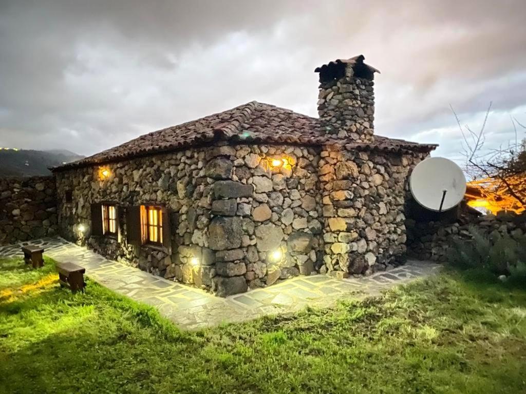 una casa de piedra con una chimenea de piedra en un campo en Finca San Pablo Icod de los Vinos, en Icod de los Vinos