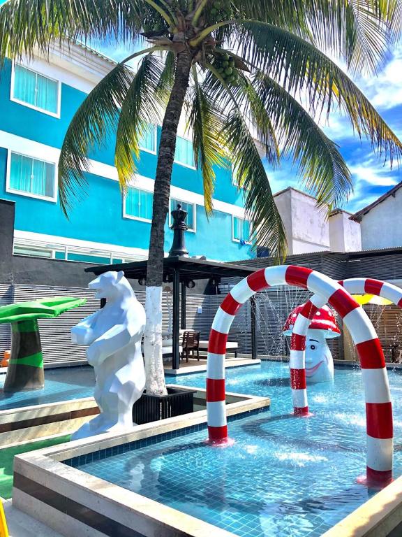 a swimming pool with a palm tree next to a building at Pousada SUN Victory in Cabo Frio