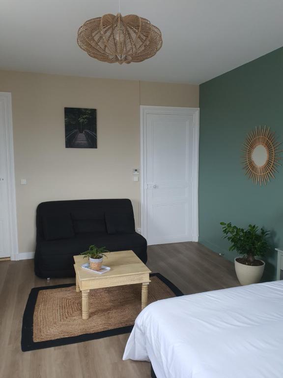 a bedroom with a bed and a couch and a table at LES 5 ESCALES in Parthenay