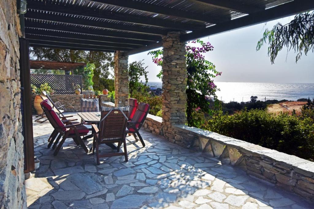 a patio with a table and chairs on a stone wall at family home with a fantastic sea view, 5 minutes from the beaches in Koundouros
